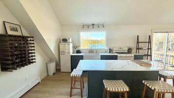 A kitchen with a central island, bar stools, a refrigerator, and a window with a view.