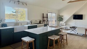 Een moderne keuken met een groot eiland, donkere kastjes en uitzicht op een meer.