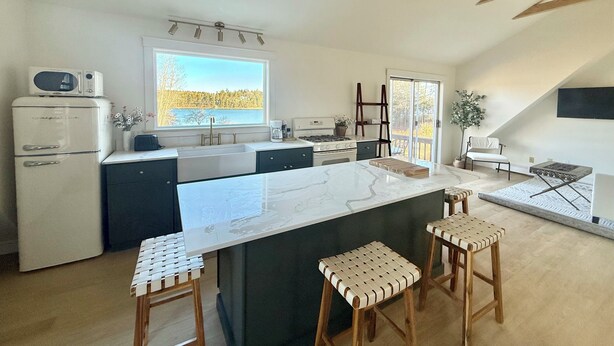 Een moderne keuken met een groot eiland, donkere kastjes en uitzicht op een meer.