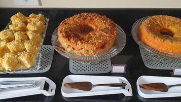 A buffet table with various baked goods, including cakes and pastries, and serving utensils.