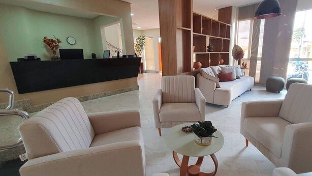 A modern hotel lobby with a reception desk, seating area, and large windows offering a view of the street. - Nordeste Palace Hotel - Glória/SE (Nossa Senhora Da Gloria)