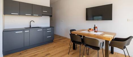 A modern kitchen with dark cabinets, a wooden dining table, and black chairs.
