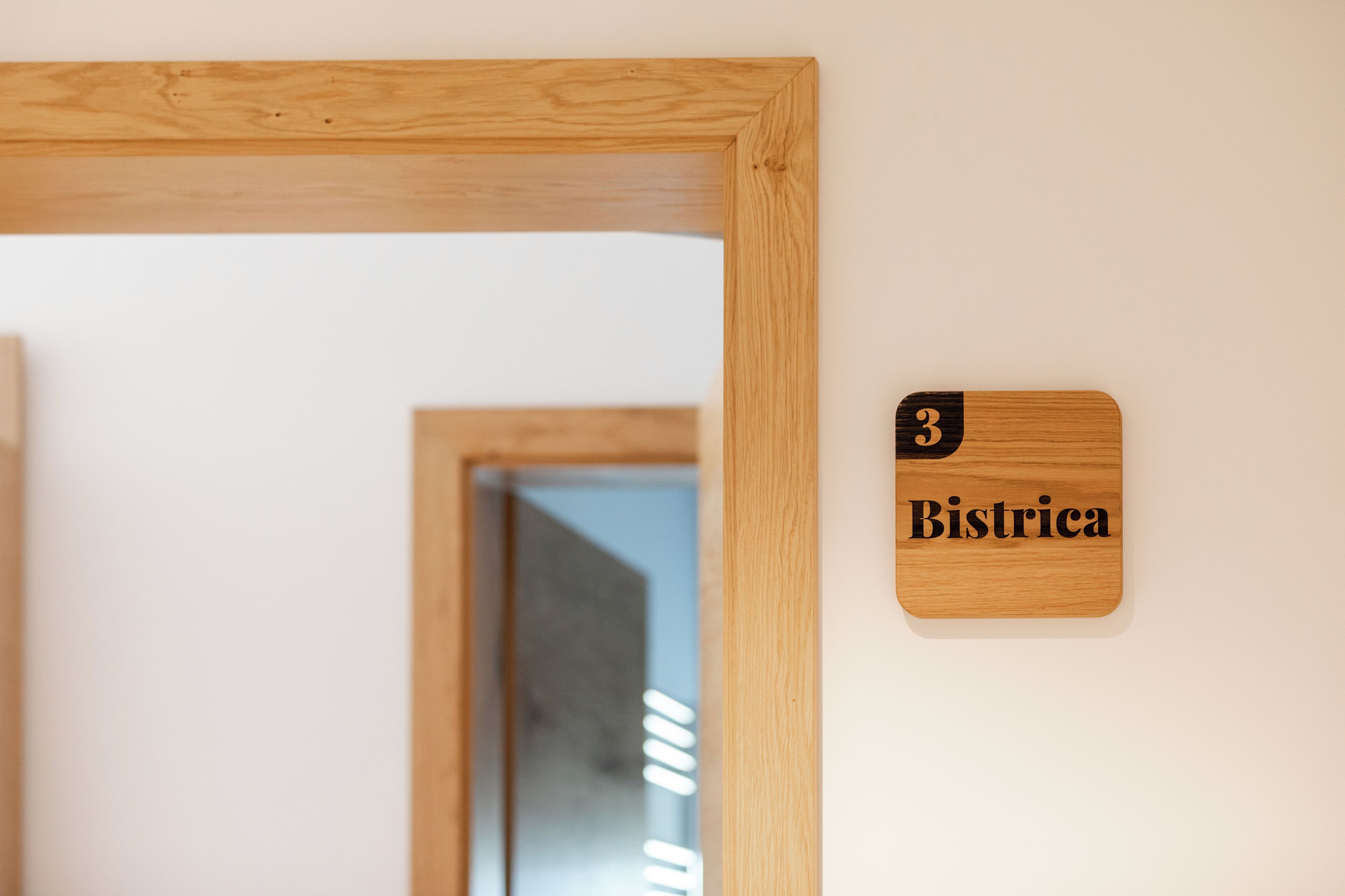 Ein hölzerner Türrahmen mit einem Schild, auf dem '3 Bistrica' steht, an einer weißen Wand.