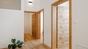 A hallway with wooden flooring, white walls, and a potted plant. - Winery and Apartments Marof (Bistrica ob Sotli)