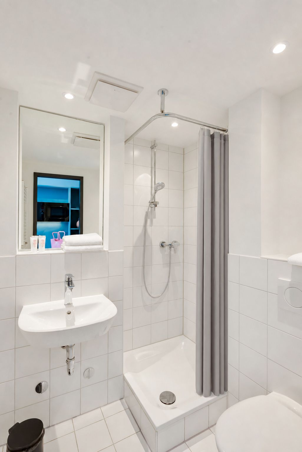A modern bathroom with a shower, sink, and toilet.