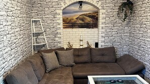 Una sala de estar acogedora con una pared de piedra, un sofá modular, una mesa de centro y una escalera contra la pared.