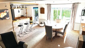 Un salón amplio con cocina, mesa de comedor y taburetes de bar.