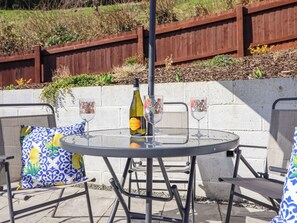 An outdoor patio with a round table, metal chairs, and a bottle of Prosecco wine. - Minffordd (Abergele)