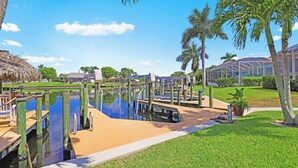 A marina with wooden docks, a thatched-roof structure, and a greenhouse.