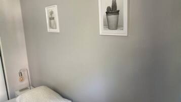Une pièce comprenant un lit, une table de chevet et deux tableaux encadrés accrochés au mur.