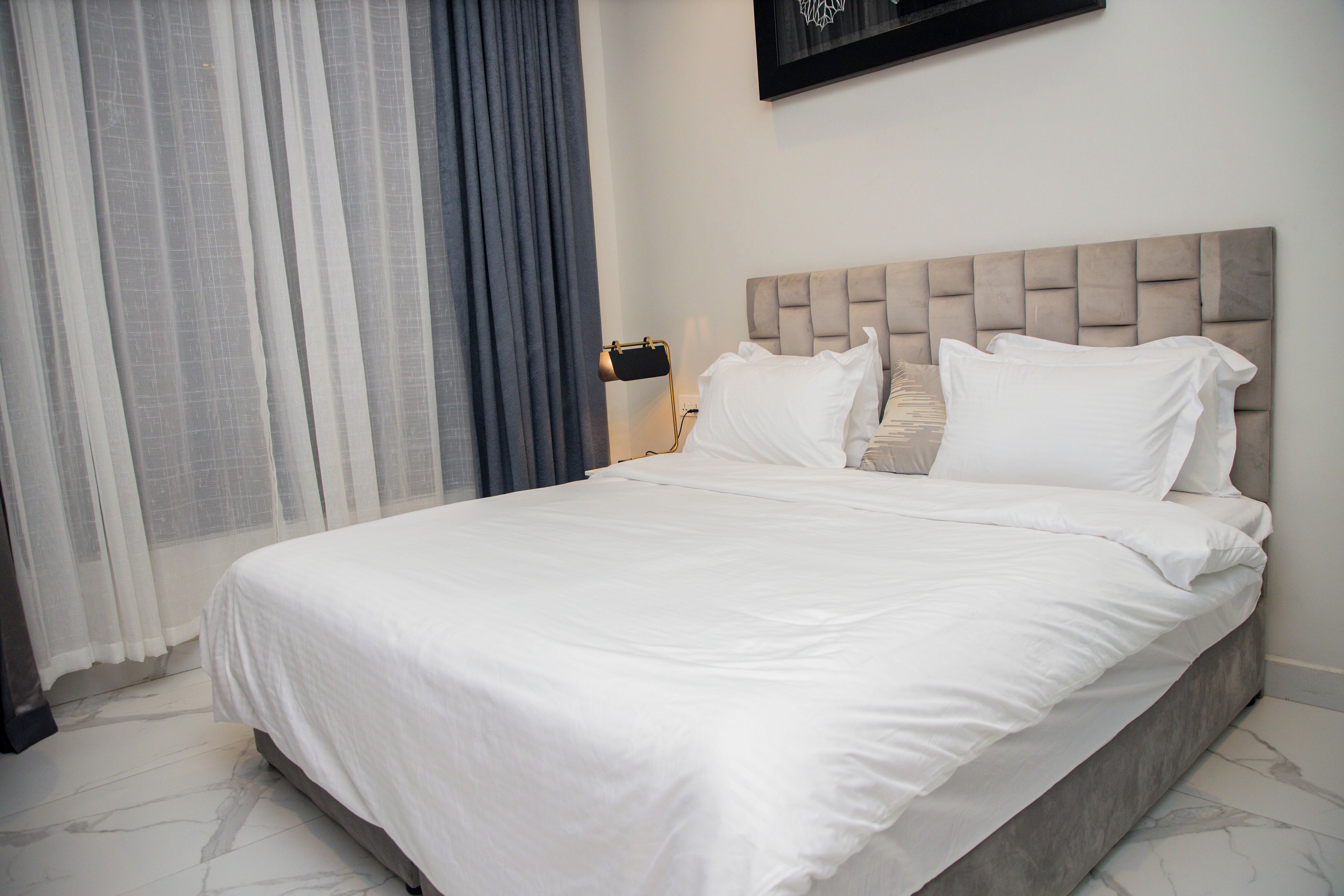 A neatly made bed with white linens in a hotel room.