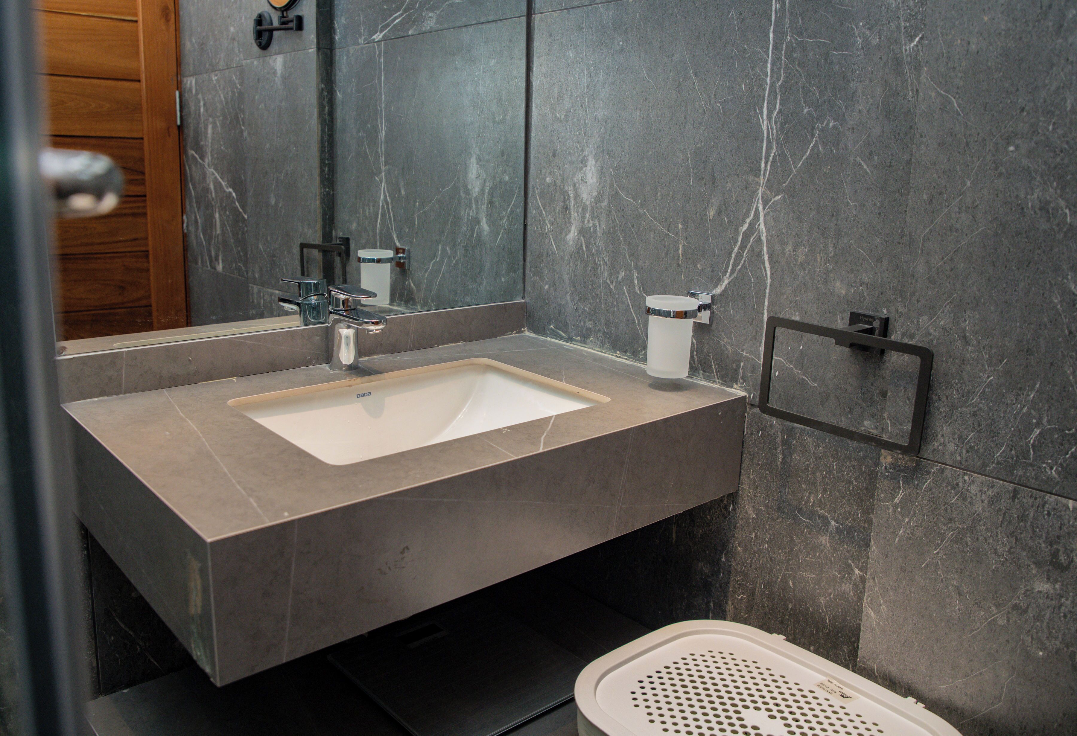Un baño moderno con un lavamanos rectangular, un espejo y un inodoro.