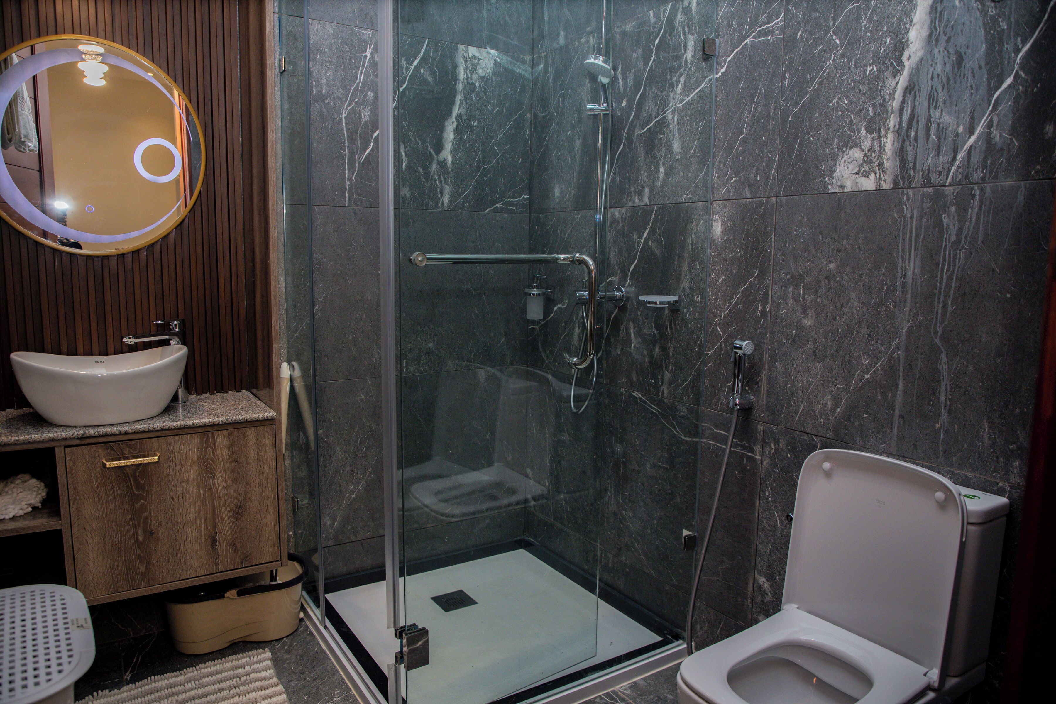 Une salle de bain moderne avec une douche à parois de verre, un lavabo blanc et un meuble-lavabo en bois.