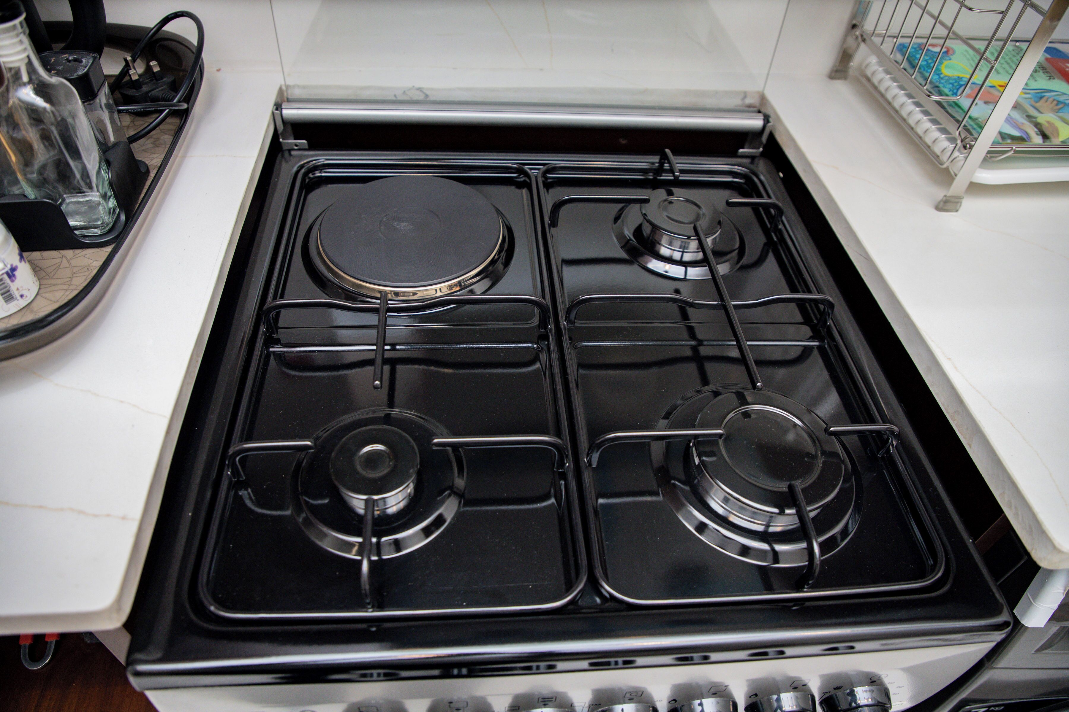 A kitchen with a gas stove, a white countertop, and a kettle.