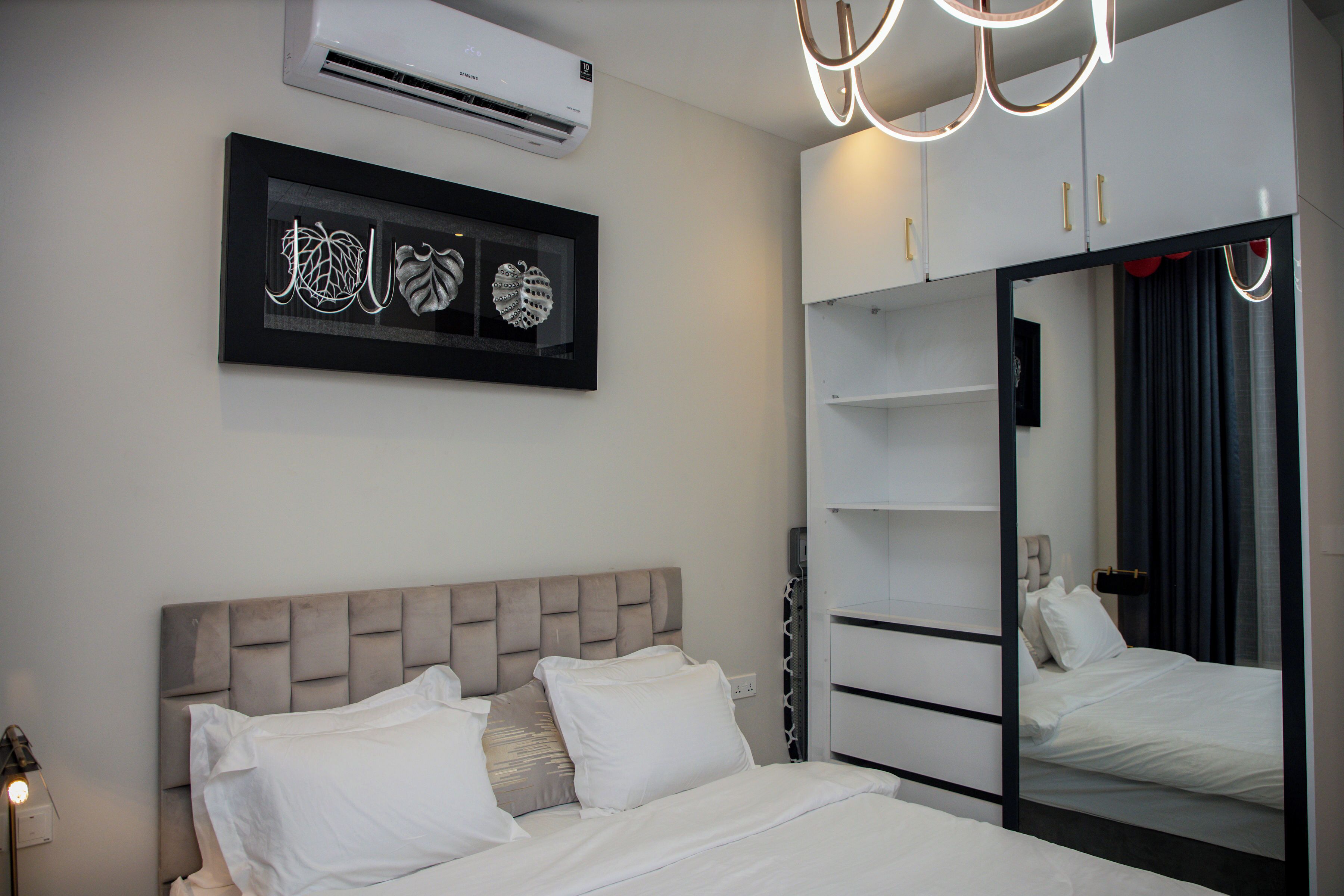 A modern bedroom with a bed, a wardrobe, and a mirror.