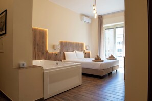 A hotel room with a large bathtub, two beds, a wooden headboard, and a view of the city through the window. - JSK Suite (Rome)