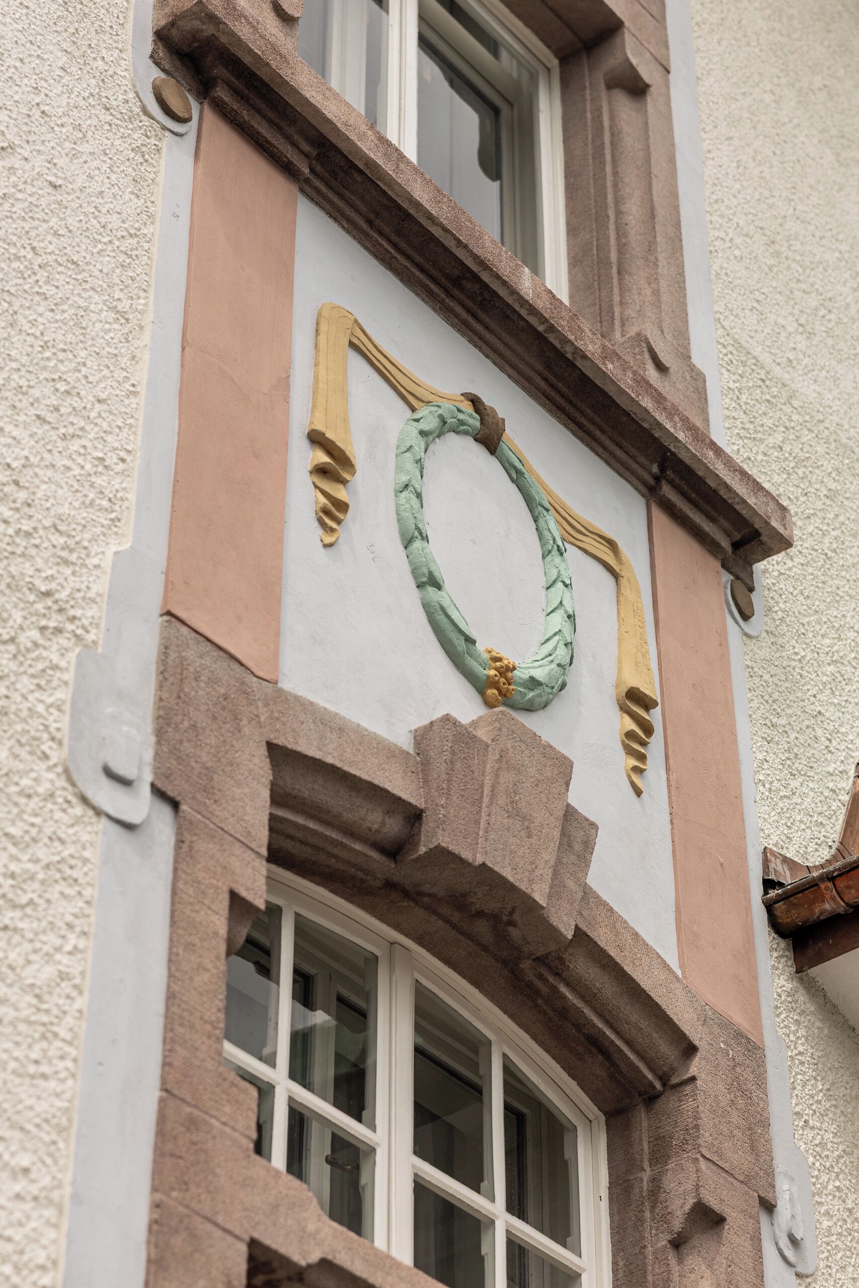 A building facade with a window, stone detailing, and a wreath.