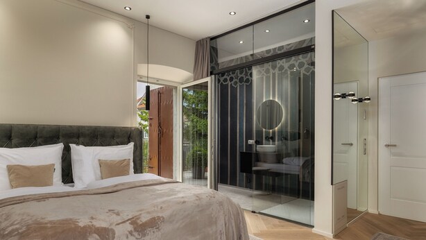 Un dormitorio moderno con una cama grande, cabina de ducha de vidrio y vistas al exterior.