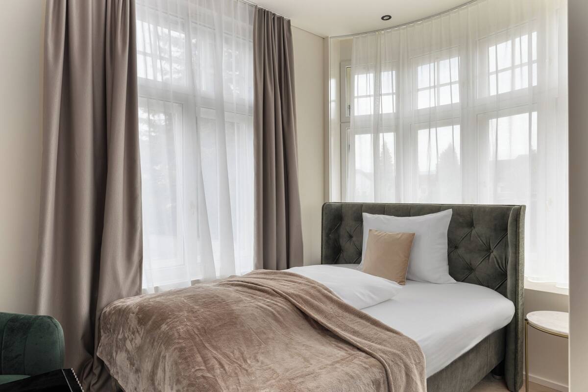 A bedroom with a bed, curtains, and a window.