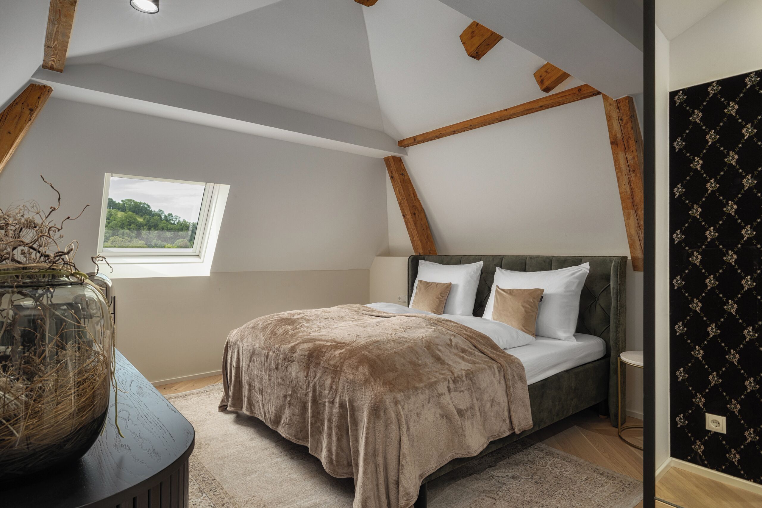 A bedroom with a large bed, a window, and a view of greenery.