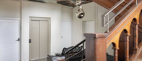 Un intérieur spacieux avec un escalier en bois, un piano et un plafond orné d’une fresque.