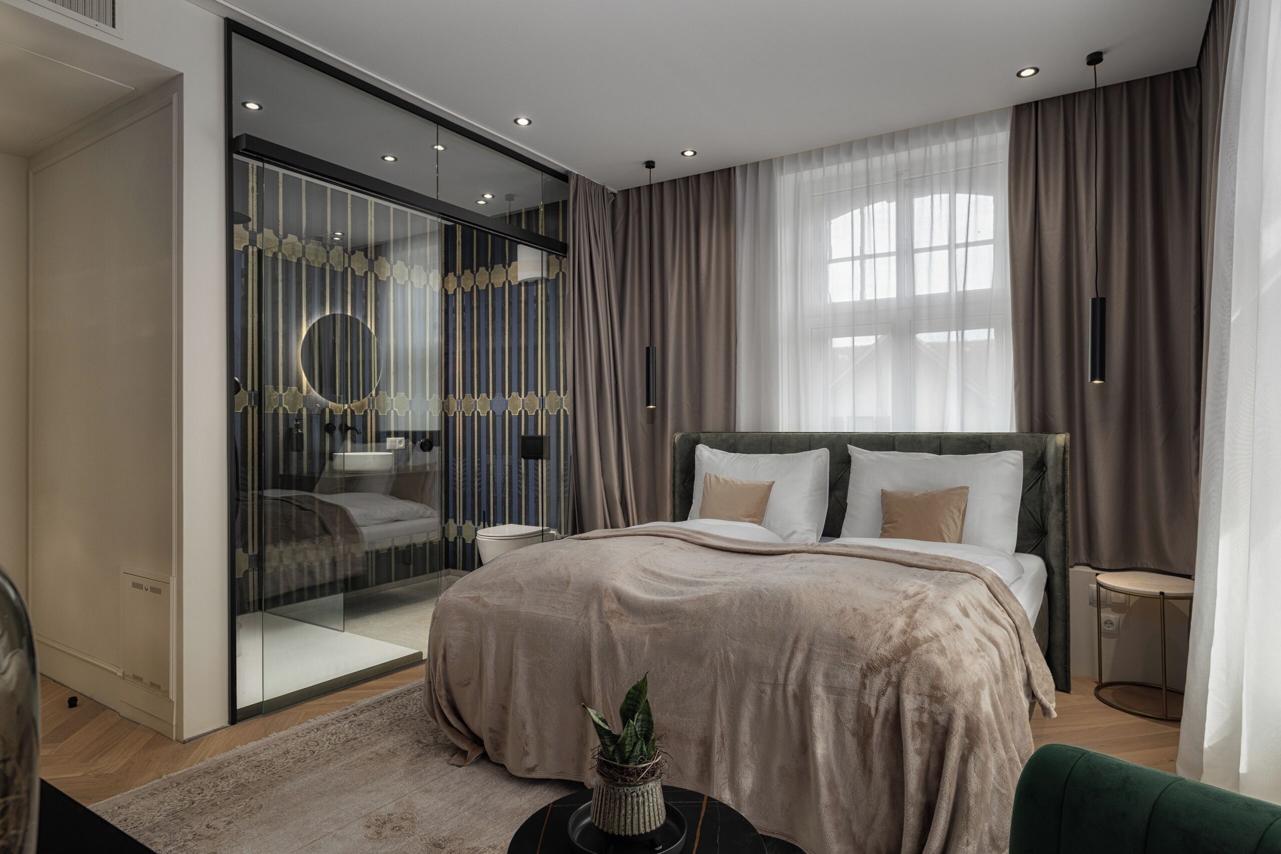 Un dormitorio moderno con una cama grande, cabina de ducha de vidrio y vistas a la ciudad.