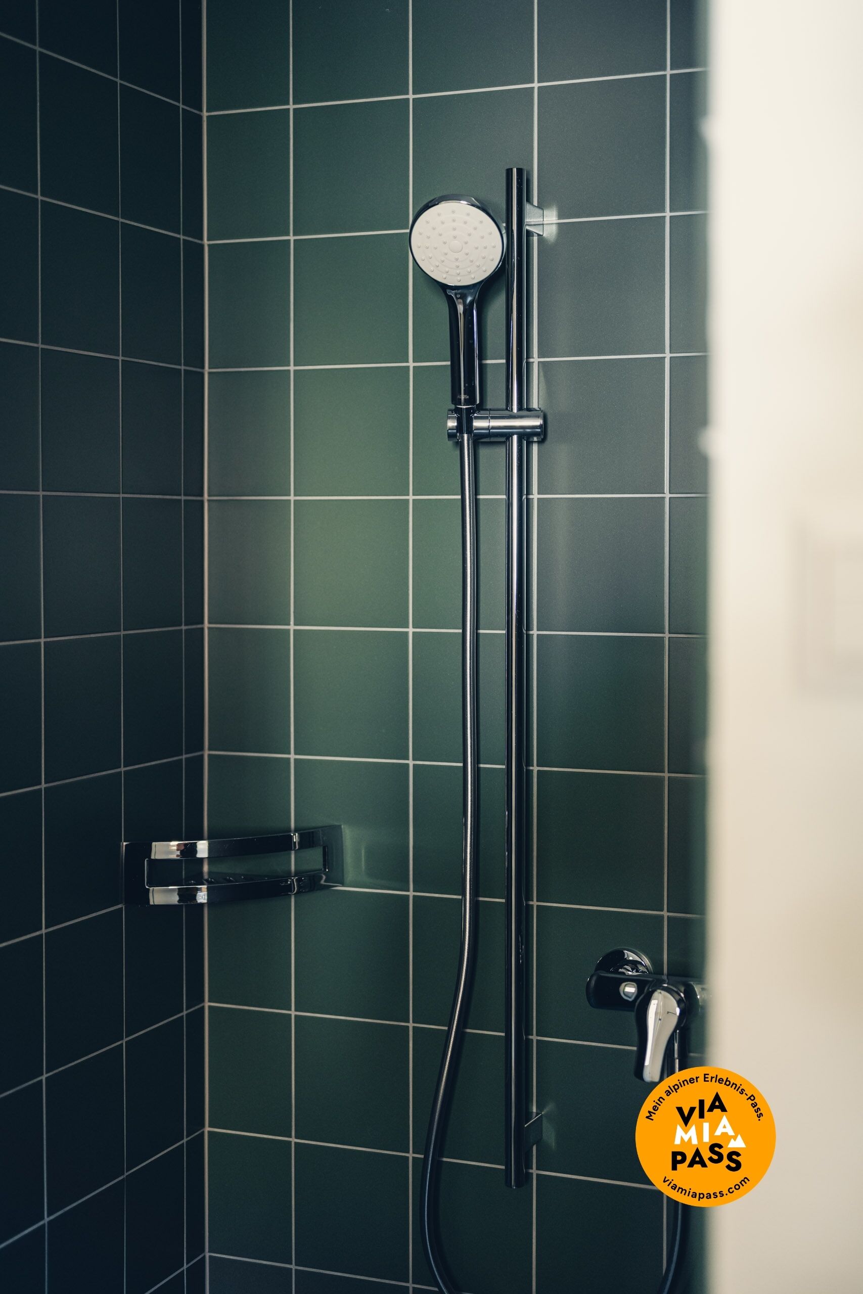 Eine Dusche mit Handbrause und am Wand montiertem Wasserhahn.