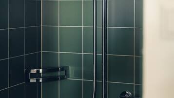 A shower with a handheld showerhead and a wall-mounted faucet.