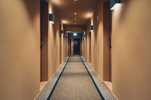 Un pasillo de hotel con suelo alfombrado y puertas a ambos lados.