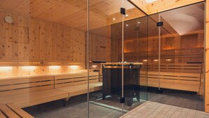Un sauna doté de bancs en bois et de parois en verre, avec un élément chauffant central.