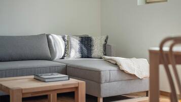 Una sala moderna con un sofá seccional gris, una mesa de centro de madera y una manta blanca.
