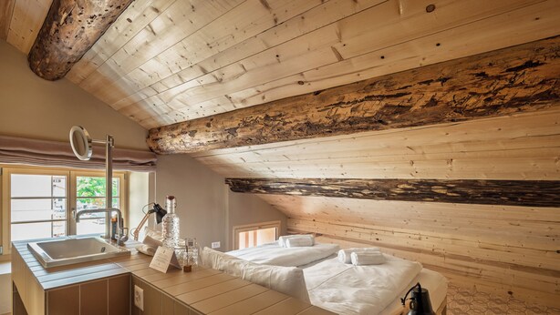 Une pièce aménagée comme une cabane en bois, avec une grande fenêtre, un lavabo, un miroir, une table de chevet et une lampe.