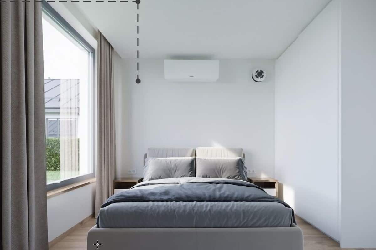 A modern bedroom with a bed, a window with curtains, a wall-mounted air conditioner, and a smoke detector.