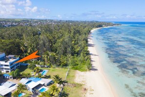 Vista aérea de una zona costera con playa, bosque denso y un resort con varias edificaciones.