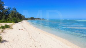 A beach with clear blue water and a sandy shore.