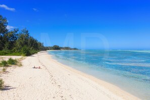Une plage avec une eau d’un bleu limpide et un rivage sablonneux.