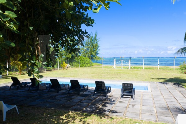 A poolside area with lounge chairs and a view of the ocean. - Le Bergamote apartment with pool on an infinity beach (Riambel)
