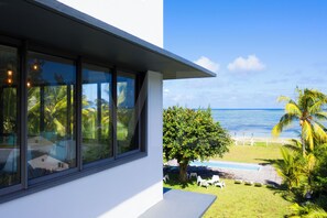 A modern house with large windows overlooking a pool and ocean view.