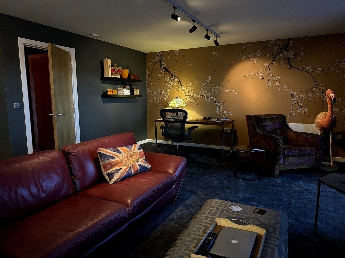 A living room with a leather sofa, a desk, a chair, and a lamp.