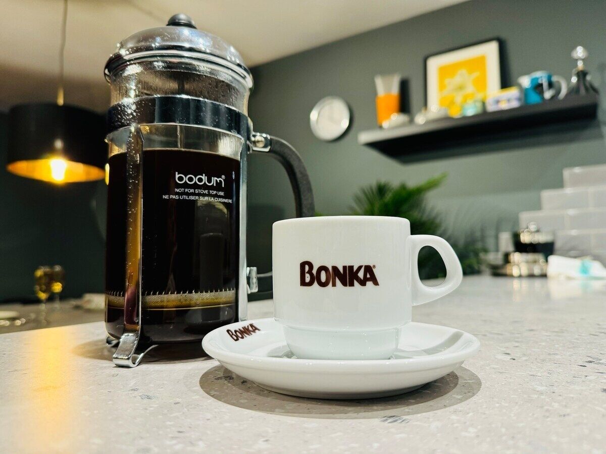 A coffee maker and a cup with the brand name "Bonka" on a kitchen counter.