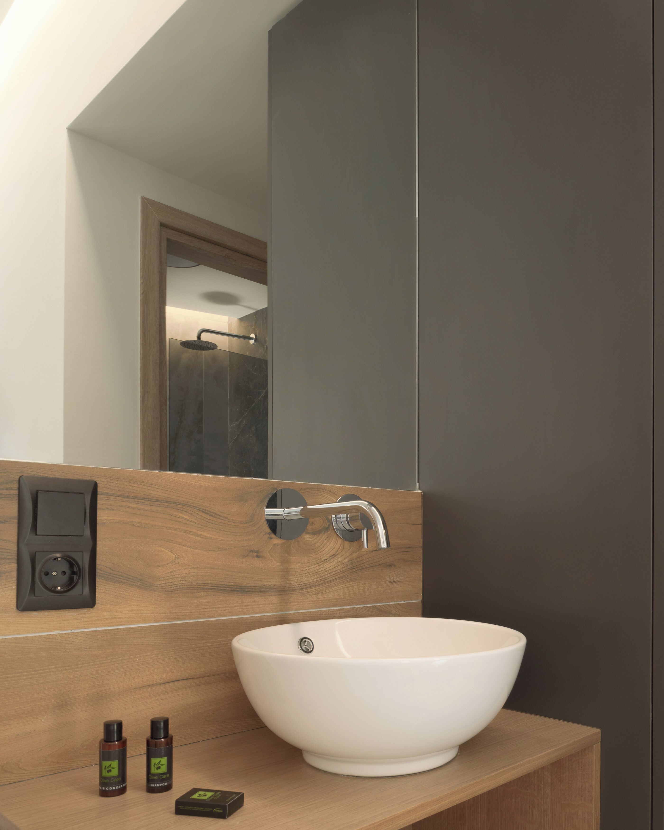 Une salle de bain moderne avec un grand miroir, un lavabo blanc et un meuble-lavabo en bois.