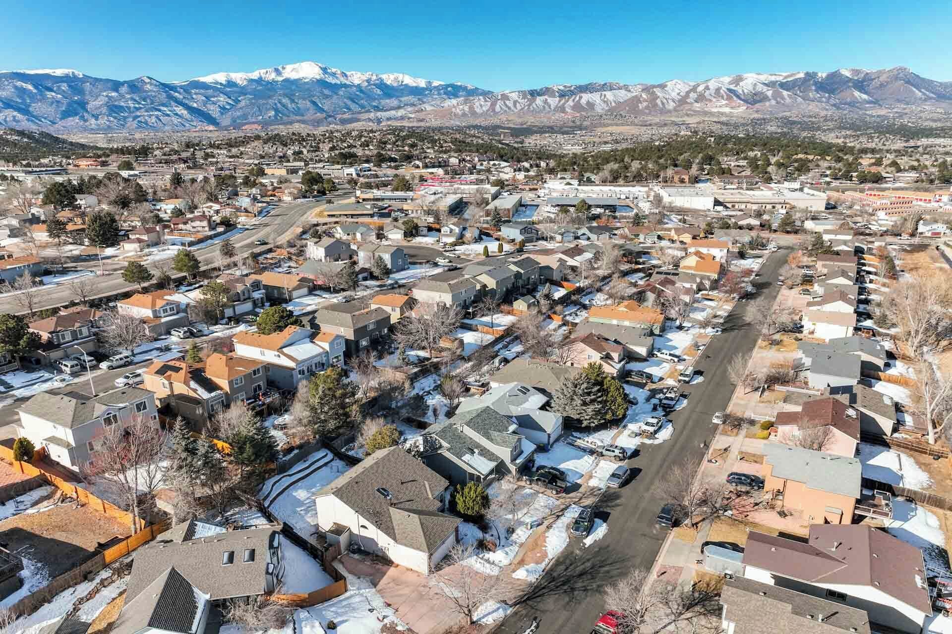 A residential area with houses, roads, and a mountain range in the background.