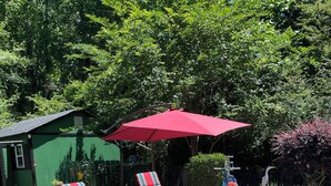 Une piscine avec deux chaises longues rayées de rouge et de bleu et un parasol rouge.