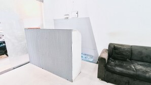 Um balcão de recepção com design estampado, um sofá cinzento e uma parede branca.