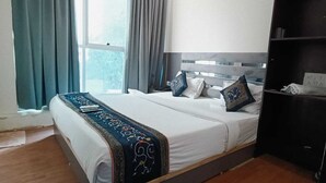 Quarto de hotel com cama, mesa de cabeceira, guarda-roupa e janela com cortinas.