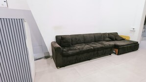 Um sofá modular em um quarto com parede branca e piso de azulejos.