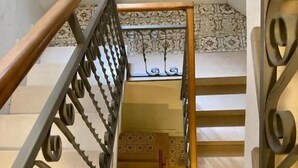 Una escalera con barandilla de madera y balaustradas metálicas ornamentales.