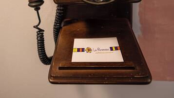 A vintage rotary dial telephone with a wooden base, mounted on a wall.