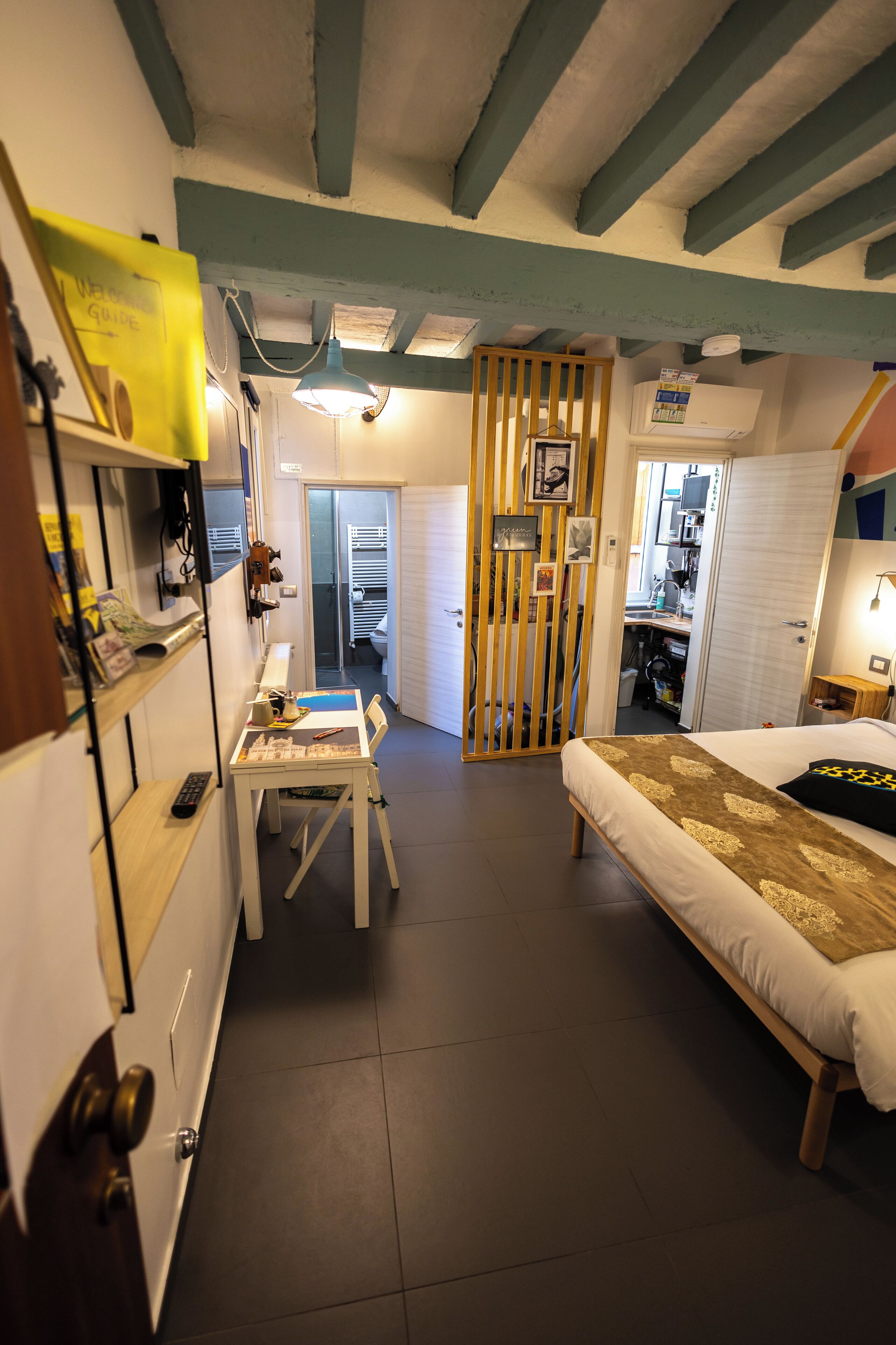 Ein Schlafzimmer mit einem Bett, einem Schreibtisch und einem Stuhl. Ein Kleiderschrank und eine Tür zu einem anderen Raum sind ebenfalls vorhanden.