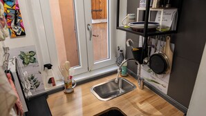 Cocina compacta con encimera de madera, un fregadero y una ventana con vistas al exterior.